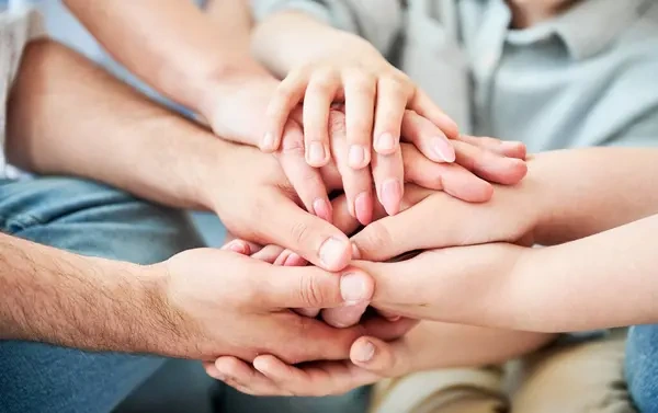 Familia y amigos uniendo manos para apoyar a su conocido a saber como dejar de tomar alcohol